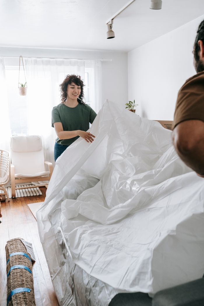Couple preparing a couch cover in a cozy home setting. Joyful home improvement experience together.
